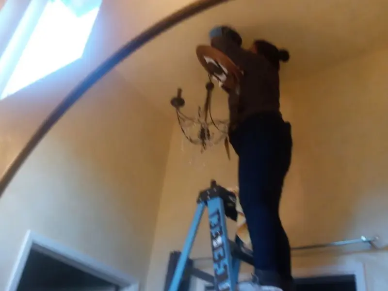 Electrician installing a chandelier in a Clinton residence